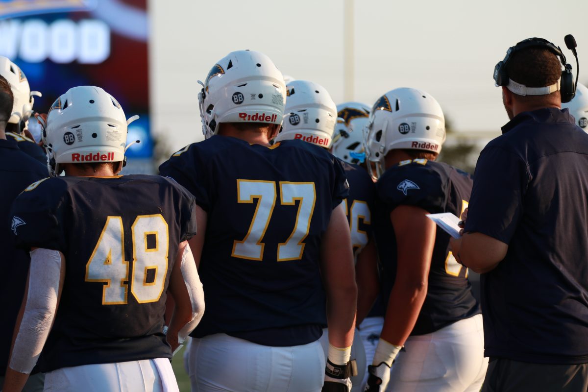 #77 Senior Ben Schug heads into the huddle to get his blocking assignment from the offensive coordinator.
