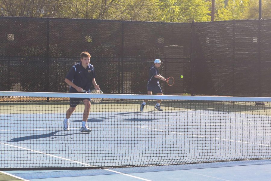 Doubles team Cole Trammel (11) and Travis Pratt (12) transition and hit the return in their match against John Paul II.