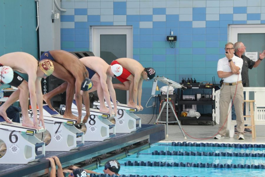 Junior Isaiah Lawshe next to swimmers from competing schools, ready to start the race