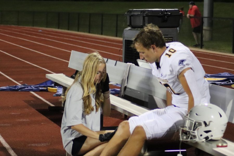 Sophomore Dani Bottems massaging Senior Troop O’Neal’s leg.