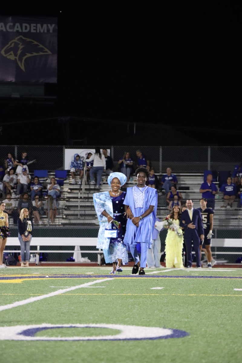 Senior Numi Adenle being escorted by his mother during the homecoming court announcement.